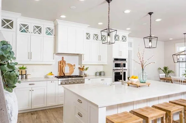 Spacious modern white kitchen with large island, pendant lighting, and wooden stools.